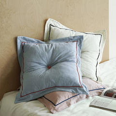 Decorative pillows with heart design on a bed against a beige wall.