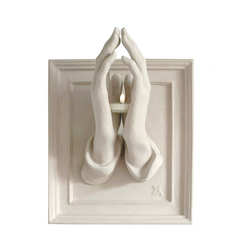 Decorative wall piece with hands holding a candle inside a frame