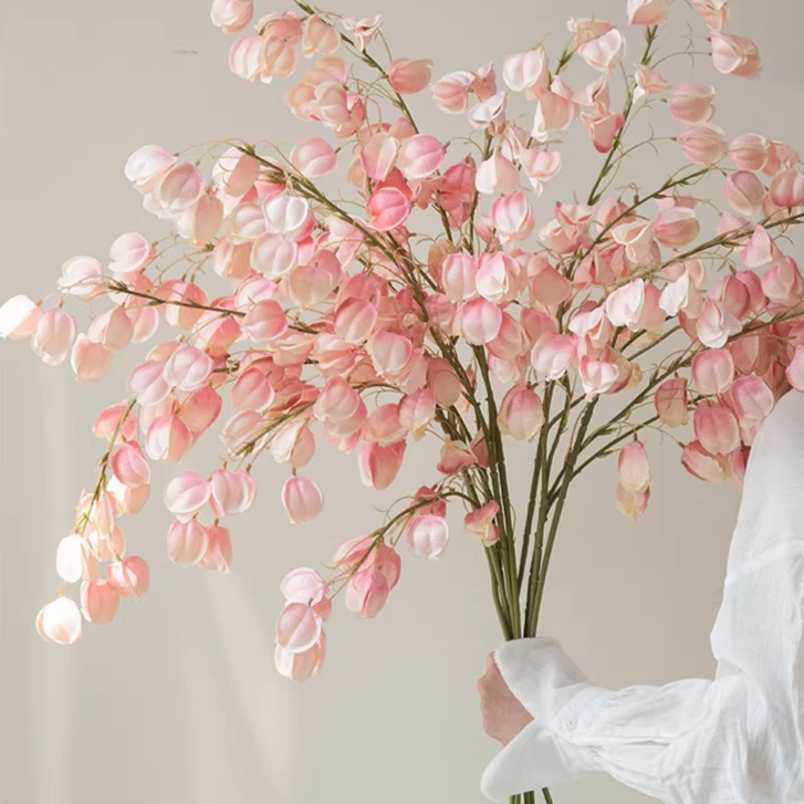 Person holding a large bouquet of pink flowers against a plain background