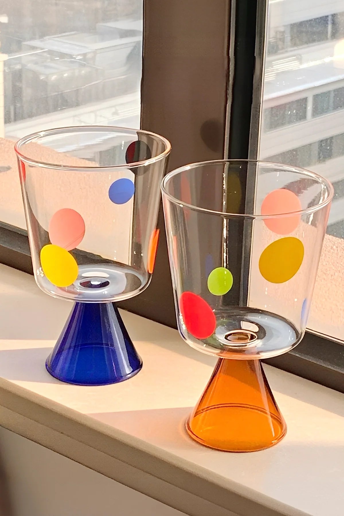 Colorful polka-dot glass goblet from TRLab Shop with vibrant dots, clear glass stem, and wide bowl for drinking or display.