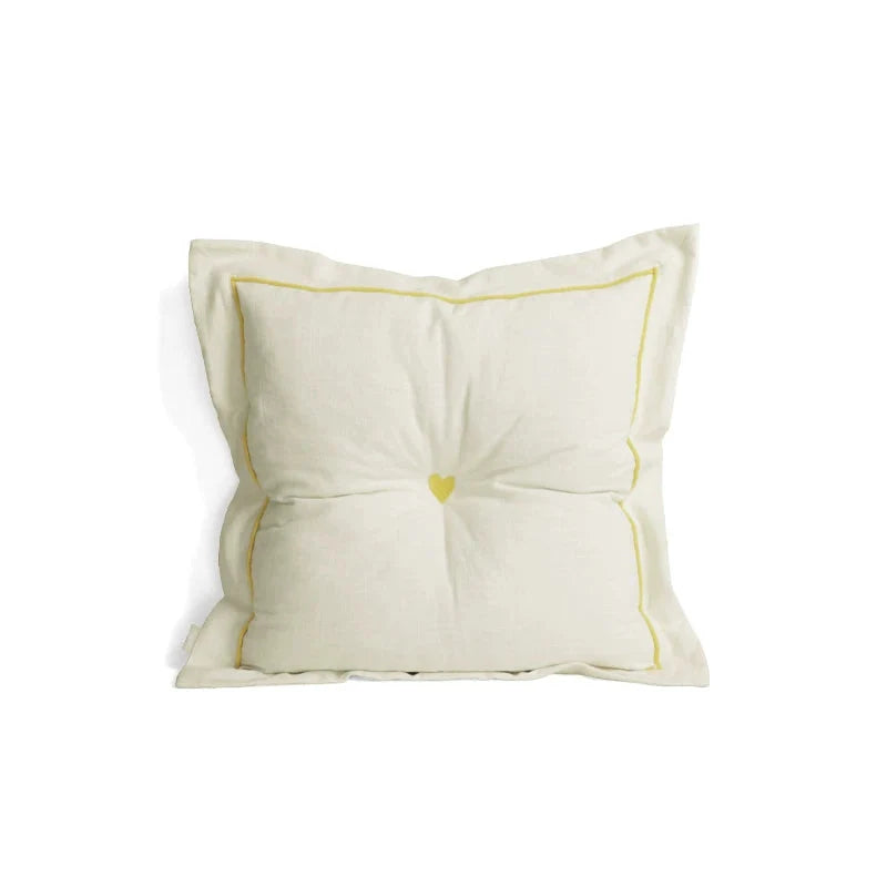White cushion with yellow heart design on a white background